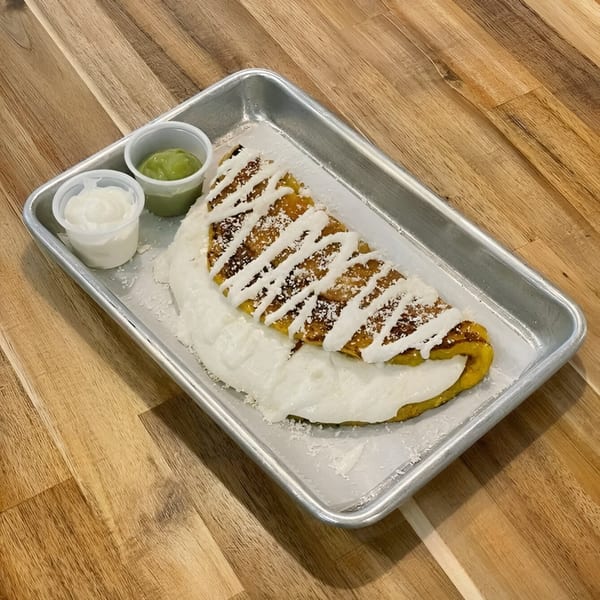 A La Fonda St quesadilla with white sauce and powdered sugar, served with two dipping sauces.