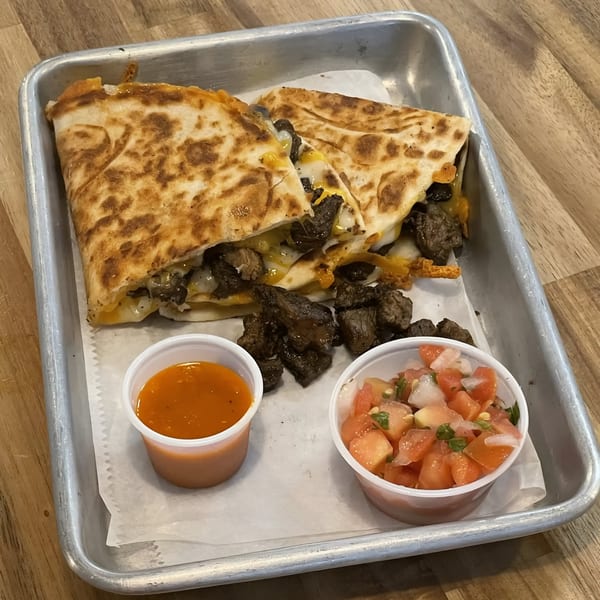 Two La Fonda St steak quesadillas with melted cheese, served with salsa and pico de gallo.